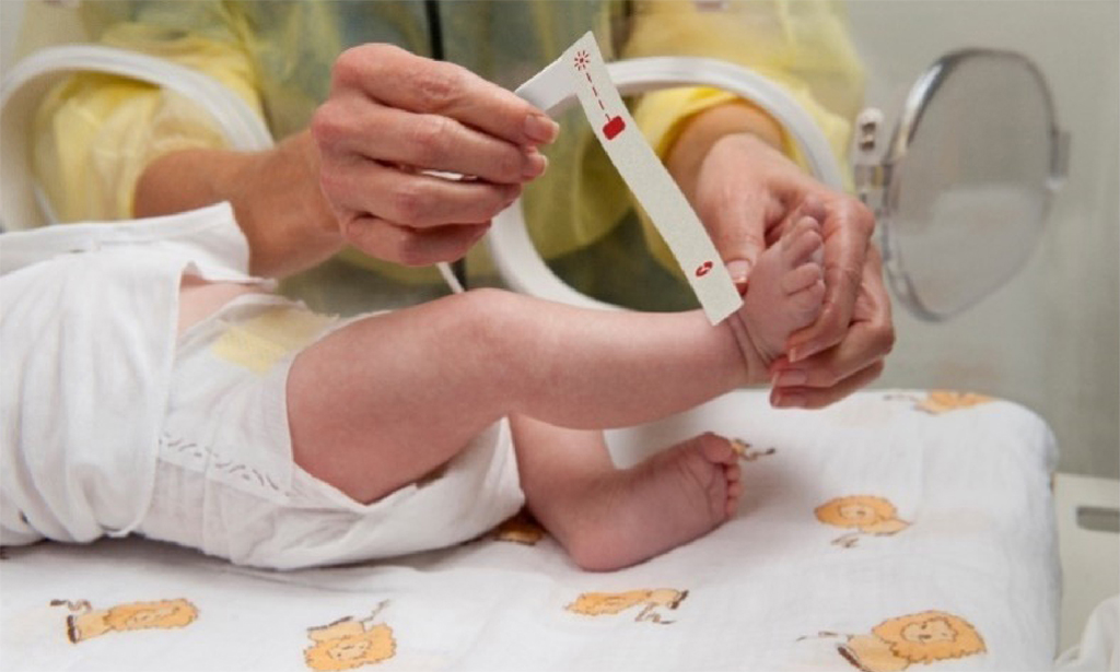 Infant in incubator in a neonatal intensive care unit having a Masimo sensor applied by hospital clinician. 